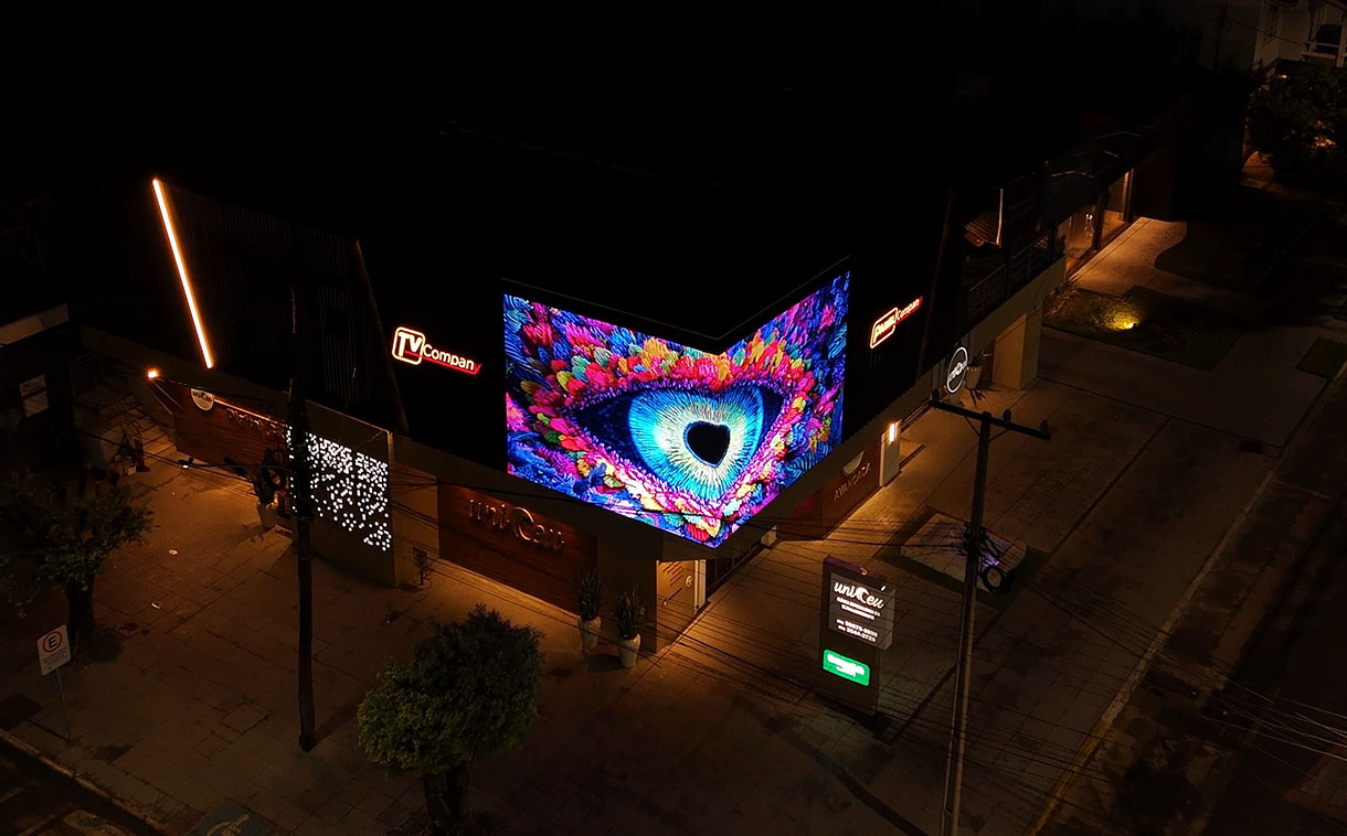 Painel de LED outdoor curvado em 90 graus instalado em Sorriso, criando efeito 3D com continuidade visual entre as duas faces da fachada.