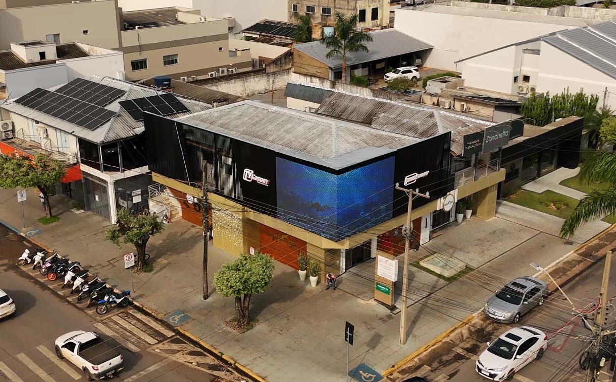 Painel de LED 3D instalado em fachada outdoor com curvatura de 90°, exibindo animações imersivas em Sorriso.